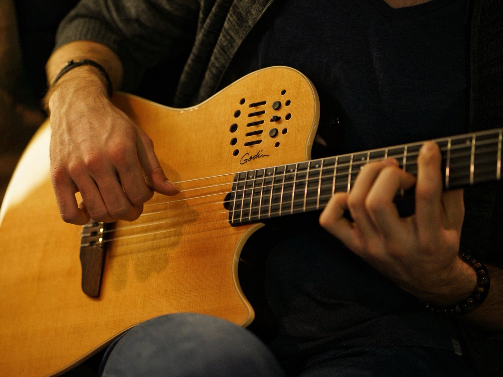 Close-up of hands playing chords on an acoustic guitar