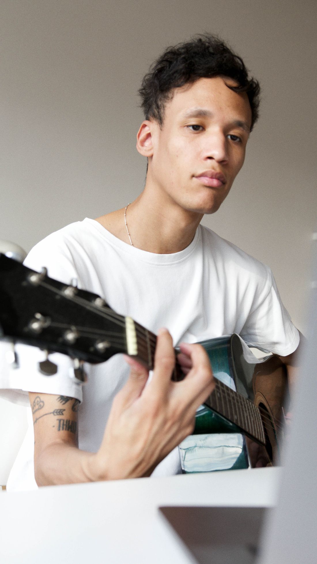 A student playing acoustic guitar while following an online lesson